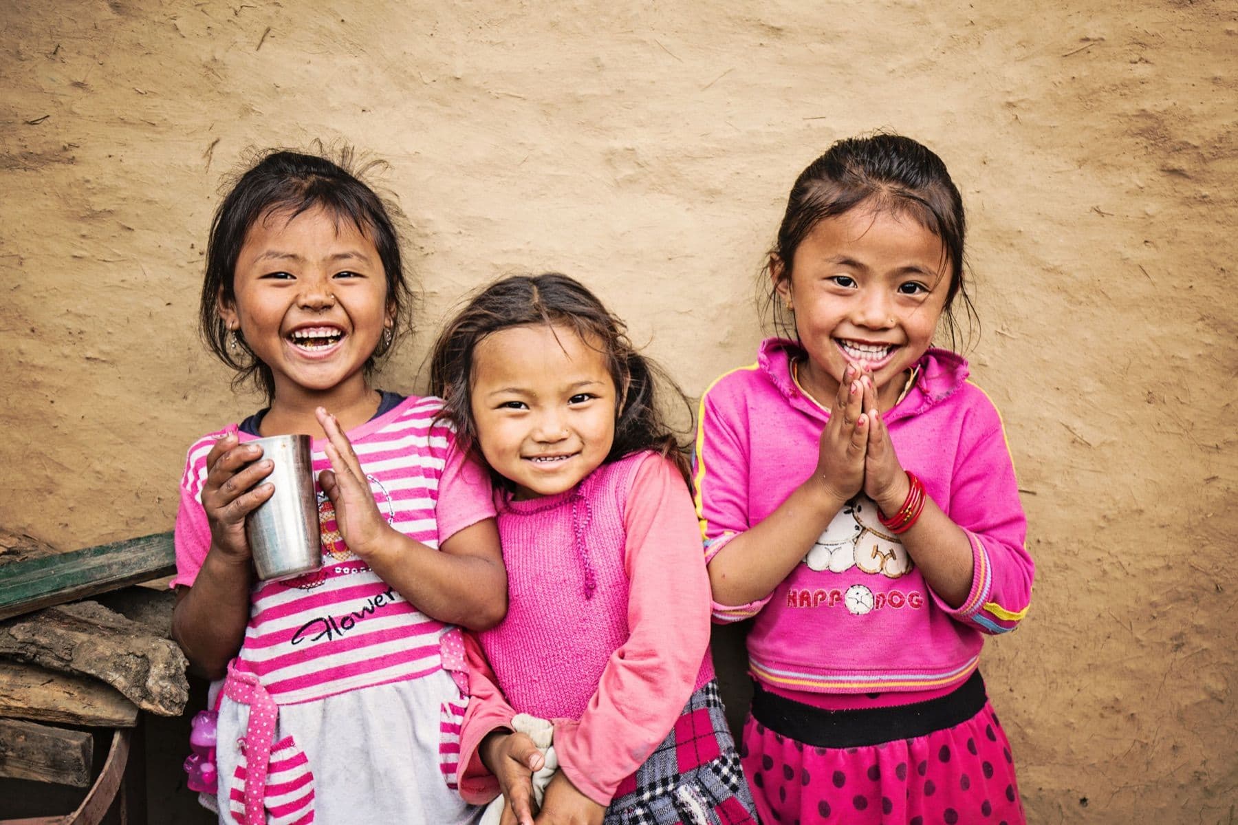 Three girls smiling together, from Reach Nepal’s photograph collection.
