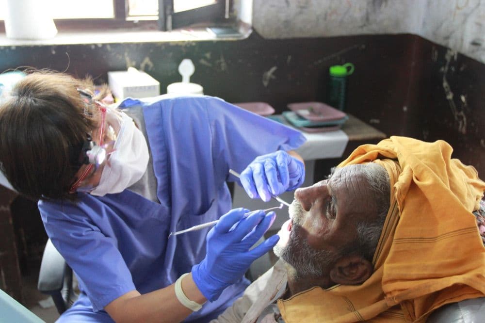 A dental professional providing care during outreach shown by Reach Nepal.